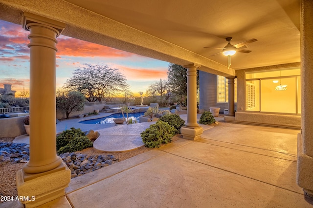 patio terrace at dusk featuring a fenced in pool and ceiling fan