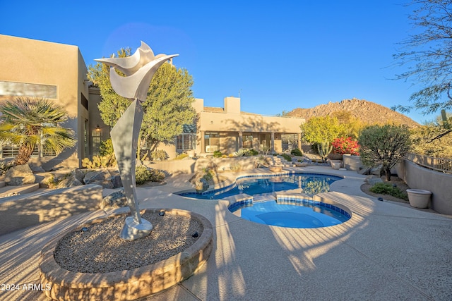 view of pool featuring a patio area, an in ground hot tub, and a mountain view