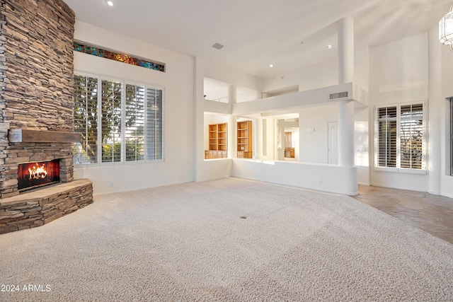 unfurnished living room with a fireplace, a towering ceiling, and carpet floors