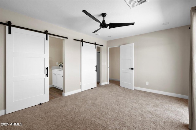 2559 E Broadway Rd, Phoenix, AZ 85040 - unfurnished bedroom featuring a barn door, light carpet, ensuite bath, and a ceiling fan