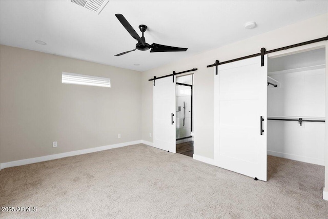 2559 E Broadway Rd, Phoenix, AZ 85040 - unfurnished bedroom featuring a barn door, carpet floors, a ceiling fan, and a walk in closet