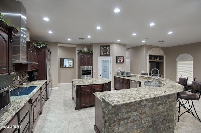 kitchen with light stone counters, stainless steel appliances, a large island, and sink