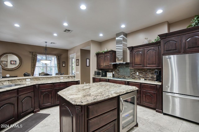 kitchen featuring appliances with stainless steel finishes, decorative light fixtures, wine cooler, dark brown cabinetry, and wall chimney range hood