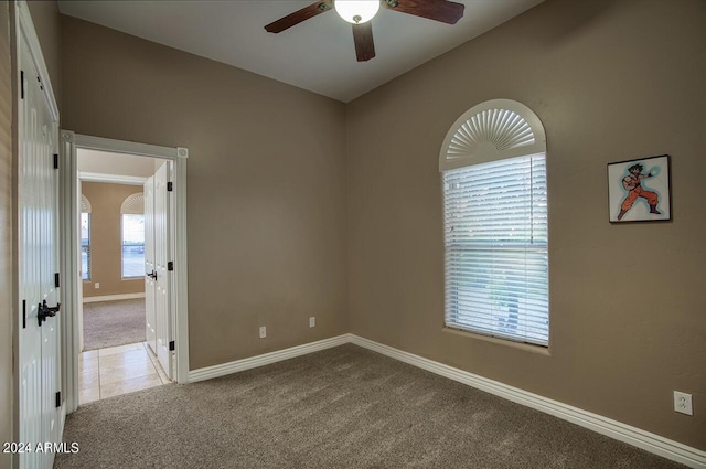 spare room featuring ceiling fan, light colored carpet, and lofted ceiling