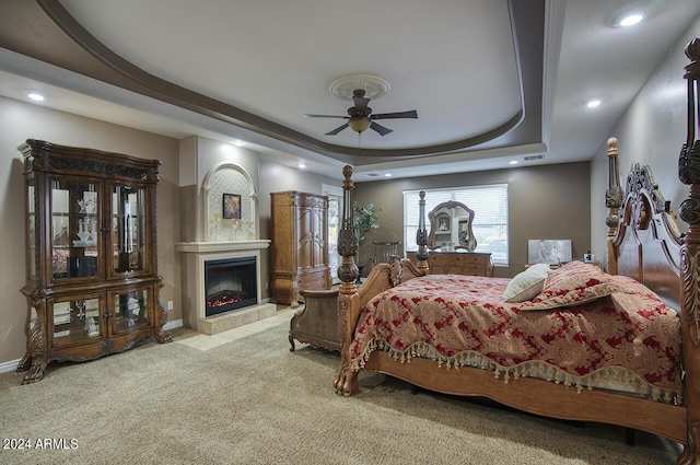 bedroom featuring ceiling fan, a tray ceiling, and light carpet