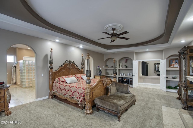 carpeted bedroom featuring a raised ceiling and ensuite bathroom