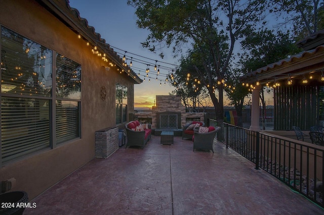 patio terrace at dusk with an outdoor living space with a fireplace