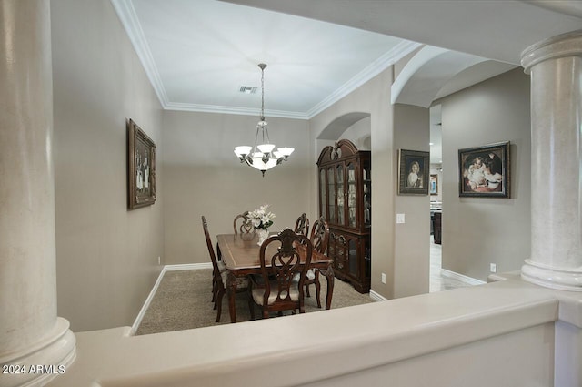 carpeted dining space featuring ornamental molding, a chandelier, and ornate columns