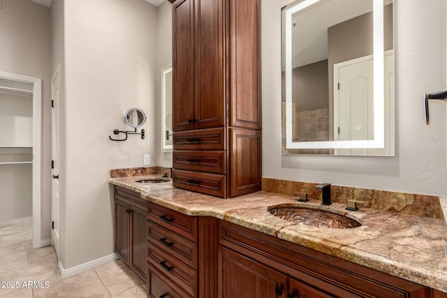 bathroom featuring double vanity, tile patterned floors, baseboards, and a sink
