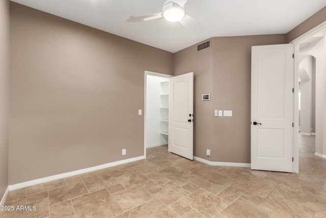 spare room with baseboards, a ceiling fan, visible vents, and arched walkways