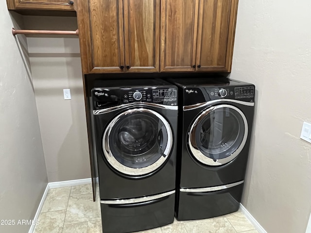 laundry area featuring tile patterned flooring, cabinet space, washing machine and dryer, and baseboards