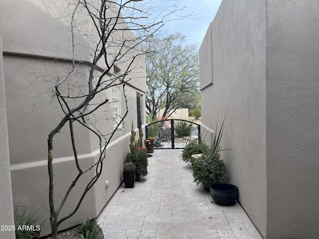 view of side of property with stucco siding, a patio, and a gate