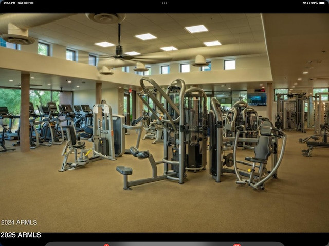 gym with a paneled ceiling, a high ceiling, and a ceiling fan