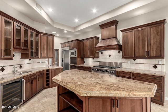 kitchen featuring beverage cooler, visible vents, custom exhaust hood, a sink, and built in appliances