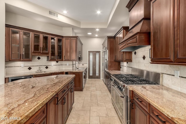 kitchen featuring a tray ceiling, double oven range, visible vents, and light stone countertops