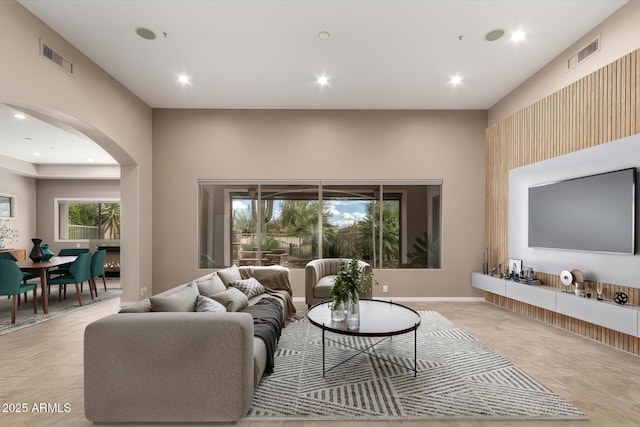 living room with arched walkways, visible vents, and recessed lighting