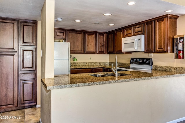 kitchen featuring kitchen peninsula, light stone counters, white appliances, sink, and light tile patterned flooring