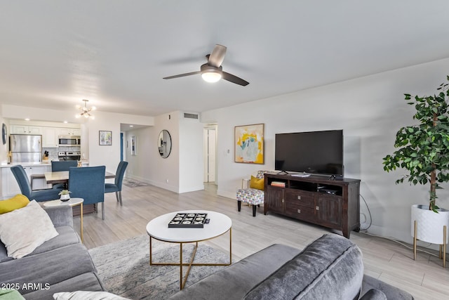 living room featuring light hardwood / wood-style flooring and ceiling fan with notable chandelier