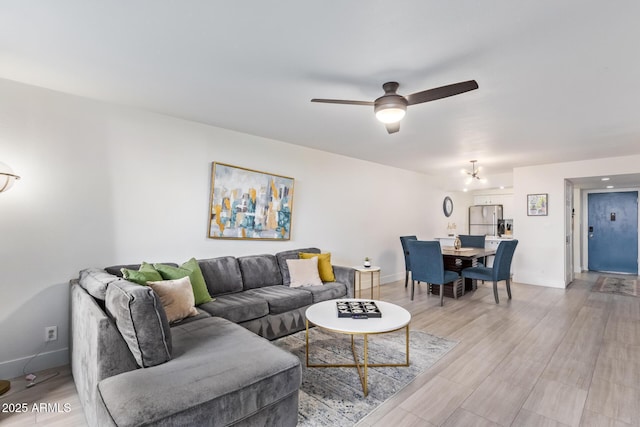 living room featuring light hardwood / wood-style flooring and ceiling fan with notable chandelier