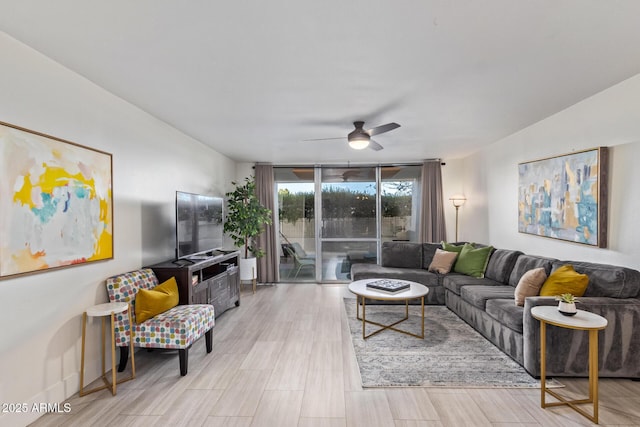 living room featuring ceiling fan, light hardwood / wood-style floors, and a wall of windows