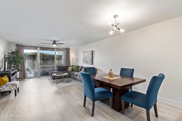 dining space featuring ceiling fan with notable chandelier and expansive windows