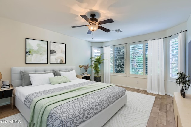 bedroom with multiple windows, light wood-type flooring, and ceiling fan