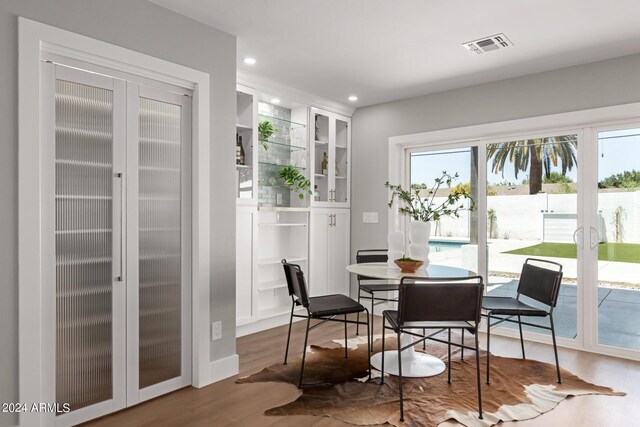 dining room featuring a wealth of natural light, built in features, french doors, and hardwood / wood-style flooring