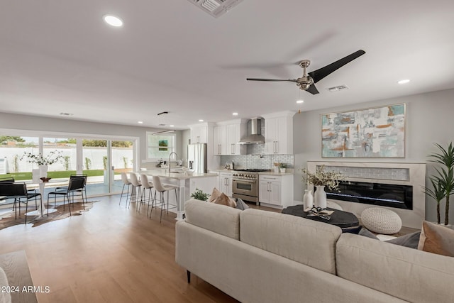 living room featuring ceiling fan, light wood-type flooring, and sink