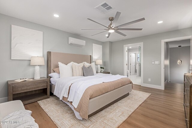 bedroom with ceiling fan, light hardwood / wood-style floors, and a wall unit AC