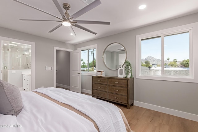 bedroom with connected bathroom, ceiling fan, and light hardwood / wood-style flooring