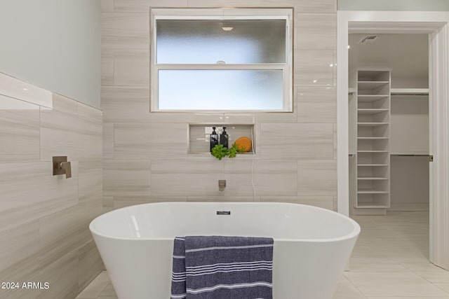 bathroom with tile patterned flooring, a bath, and tile walls