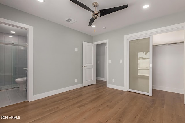 unfurnished bedroom with hardwood / wood-style flooring, ceiling fan, ensuite bathroom, and a closet