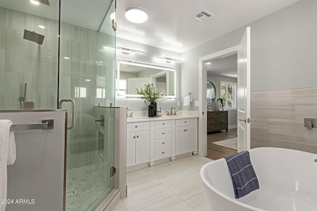 bathroom with shower with separate bathtub, vanity, tile patterned floors, and tile walls