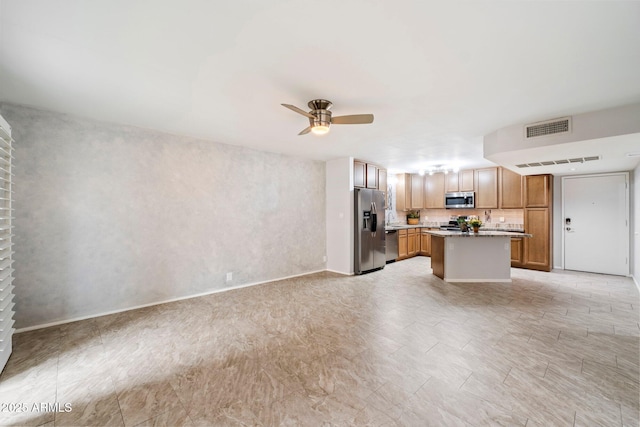 kitchen with ceiling fan, decorative backsplash, stainless steel appliances, and a kitchen island