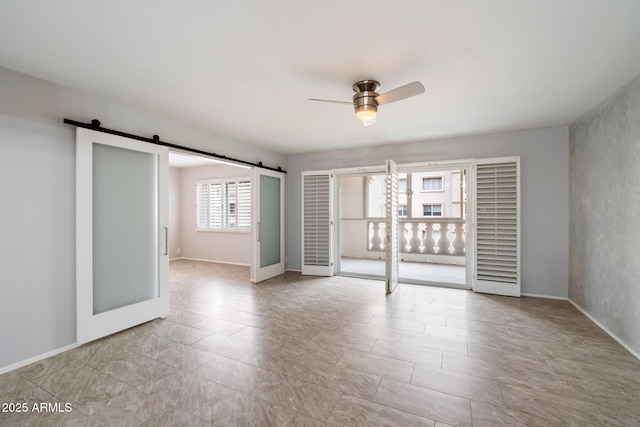 unfurnished room featuring ceiling fan and a barn door