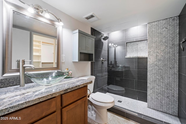 bathroom with tiled shower, tile patterned floors, toilet, and vanity