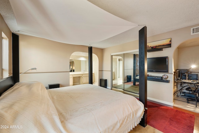 bedroom with ensuite bathroom and wood-type flooring