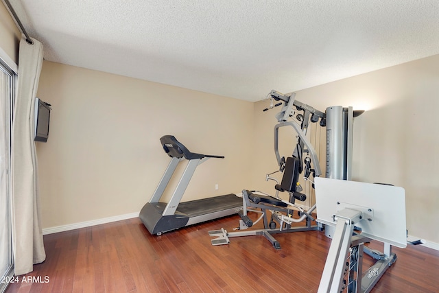 exercise area featuring dark wood-type flooring and a textured ceiling