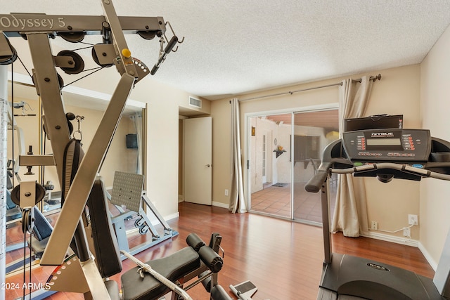 exercise room with hardwood / wood-style floors and a textured ceiling