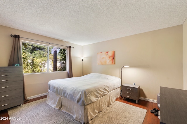 bedroom with dark wood-type flooring and a textured ceiling