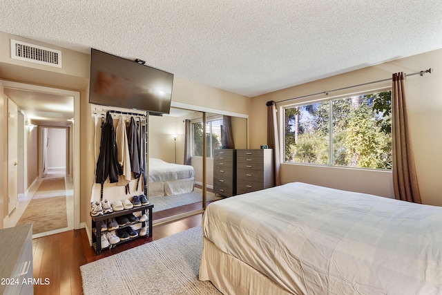 bedroom featuring dark wood-type flooring, a closet, and a textured ceiling