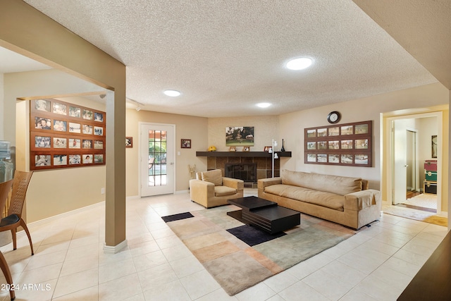 living room with a fireplace, a textured ceiling, and light tile patterned floors