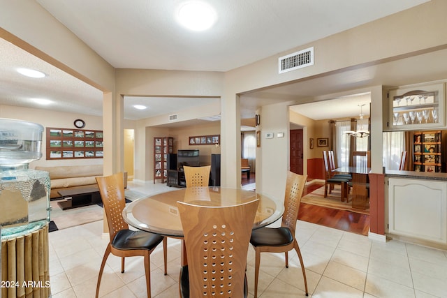 tiled dining room featuring a notable chandelier and a textured ceiling