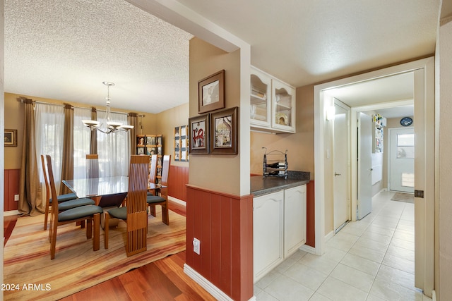 kitchen with white cabinetry, hanging light fixtures, a textured ceiling, and light hardwood / wood-style floors