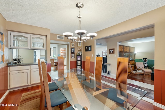 dining room featuring a textured ceiling, wood-type flooring, and an inviting chandelier