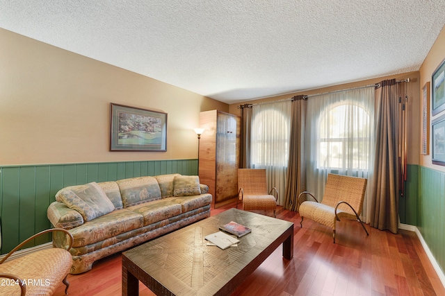 living room with wood walls, a textured ceiling, and hardwood / wood-style flooring