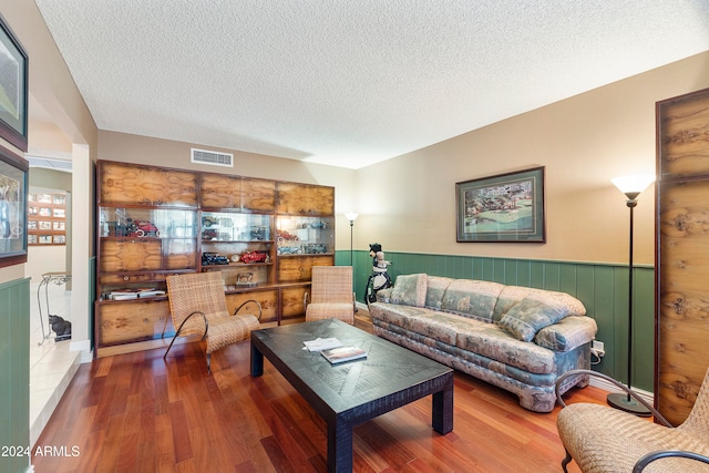 living room featuring a textured ceiling, hardwood / wood-style flooring, and wooden walls