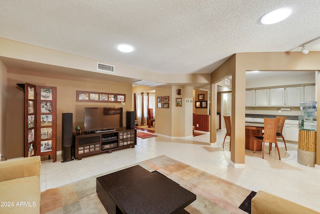 tiled living room featuring a textured ceiling and track lighting