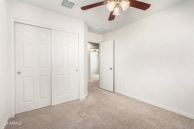 unfurnished bedroom with light carpet, a closet, and ceiling fan