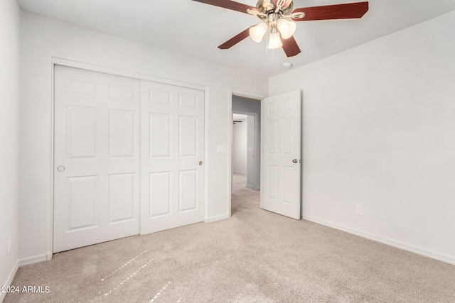 unfurnished bedroom featuring light carpet, a closet, and ceiling fan